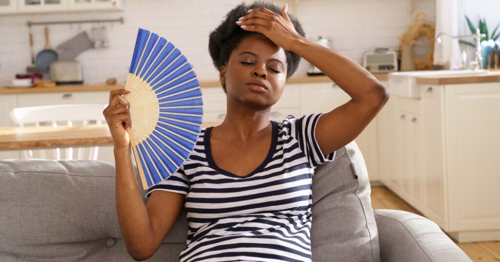 woman holding fan to cool off