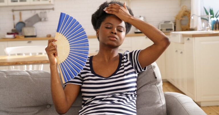 woman holding fan to cool off