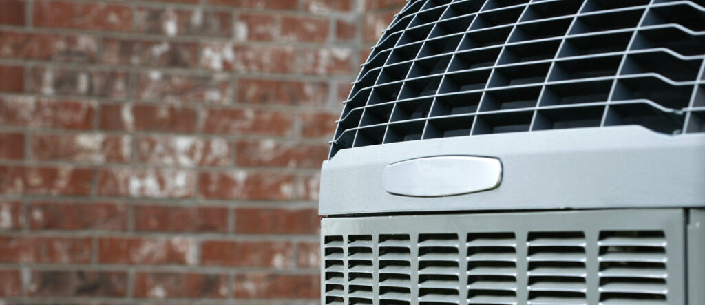 Close-up of high-efficiency modern AC unit on brick wall background.