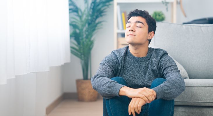 young man sitting on floor deep breathing