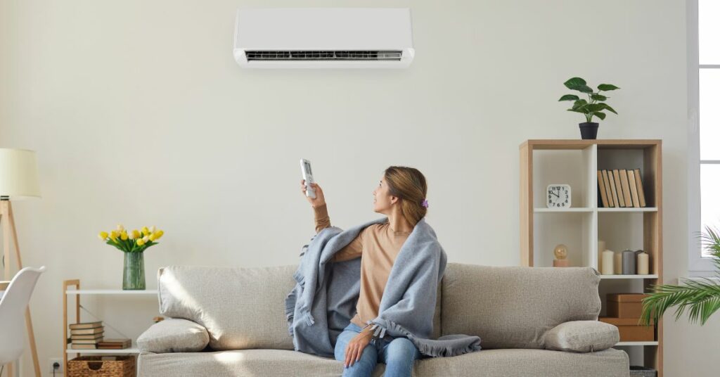 woman sitting on couch turning on ductless mini split air conditioner